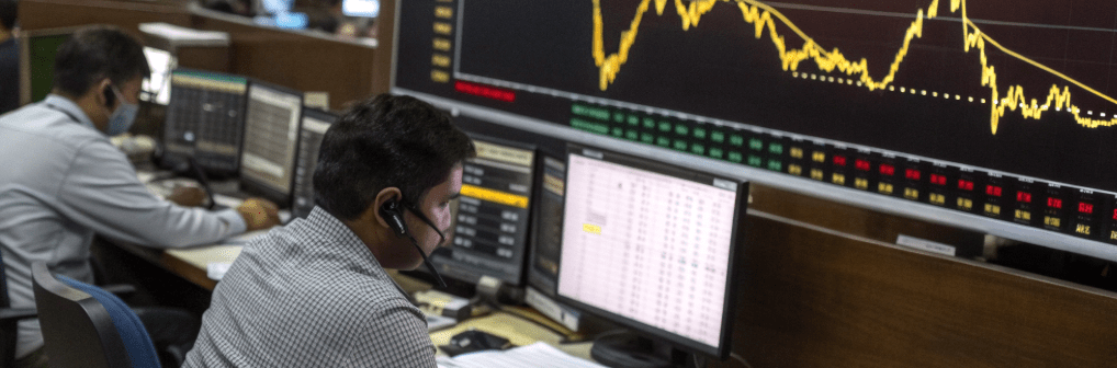Traders monitoring gold price movements on multiple screens amid volatile market conditions