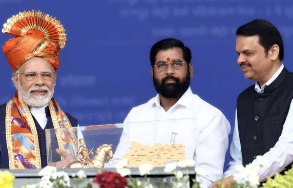 Indian Prime Minister in traditional turban standing with Maharashtra leaders Eknath Shinde and Devendra Fadnavis during a public event, symbolizing political unity and Thane’s influence